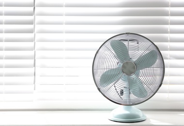 Photo of Modern electric fan on window sill indoors. Space for text