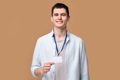 Photo of Smiling man showing empty badge on beige background