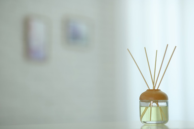 Aromatic reed air freshener on table indoors. Space for text