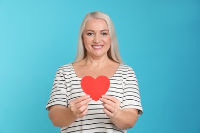 Photo of Portrait of mature woman with decorative paper heart on color background