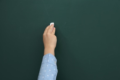 Photo of Little child writing on chalkboard, closeup. Space for text