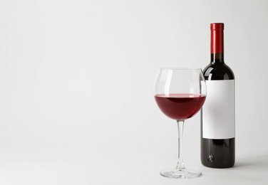Photo of Bottle and glass with delicious red wine on white background