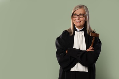 Photo of Smiling senior judge with gavel on green background. Space for text