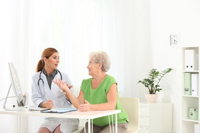 Photo of Doctor working with elderly patient in hospital. Space for text