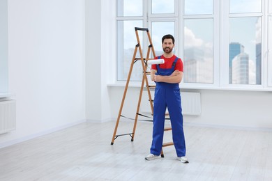 Photo of Handyman with roller in room. Ceiling painting