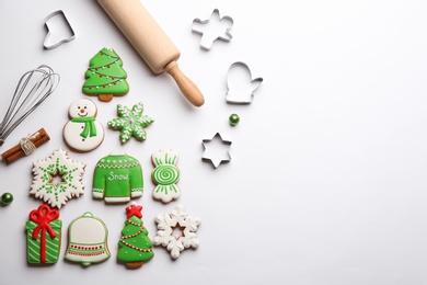 Photo of Kitchen utensils near Christmas tree shape made of delicious gingerbread cookies on white background, flat lay. Space for text