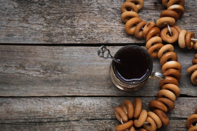 Photo of Bunch of delicious ring shaped Sushki (dry bagels) and tea on wooden table, flat lay. Space for text