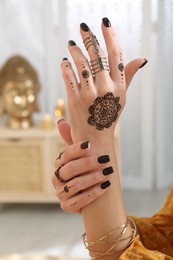 Photo of Woman with henna tattoo on hand indoors, closeup. Traditional mehndi ornament
