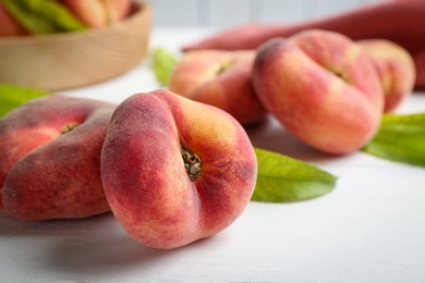 Fresh ripe donut peaches on white wooden table, closeup