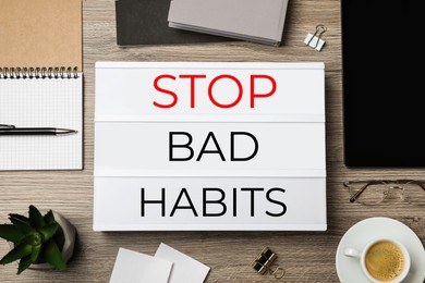 Image of Lightbox with phrase Stop Bad Habits, cup of coffee and stationery on wooden table, flat lay