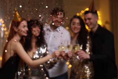 Photo of Blurred viewhappy friends clinking glasses of sparkling wine at birthday party indoors