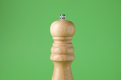 Photo of One wooden shaker on green background, closeup