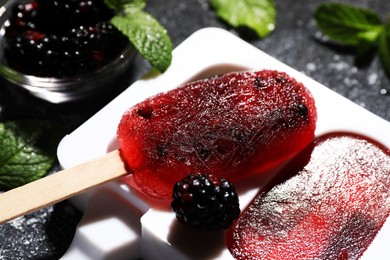 Photo of Mold with tasty blackberry ice pops on dark textured table, closeup. Fruit popsicle