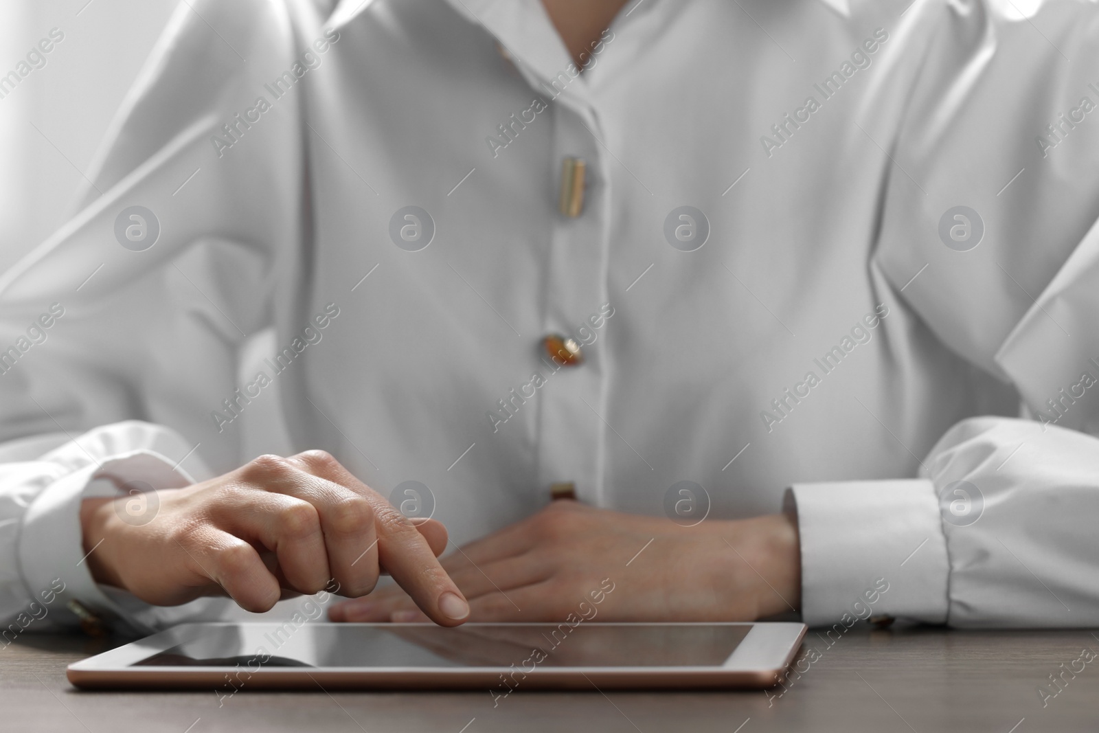 Photo of Closeup view of woman using modern tablet at table