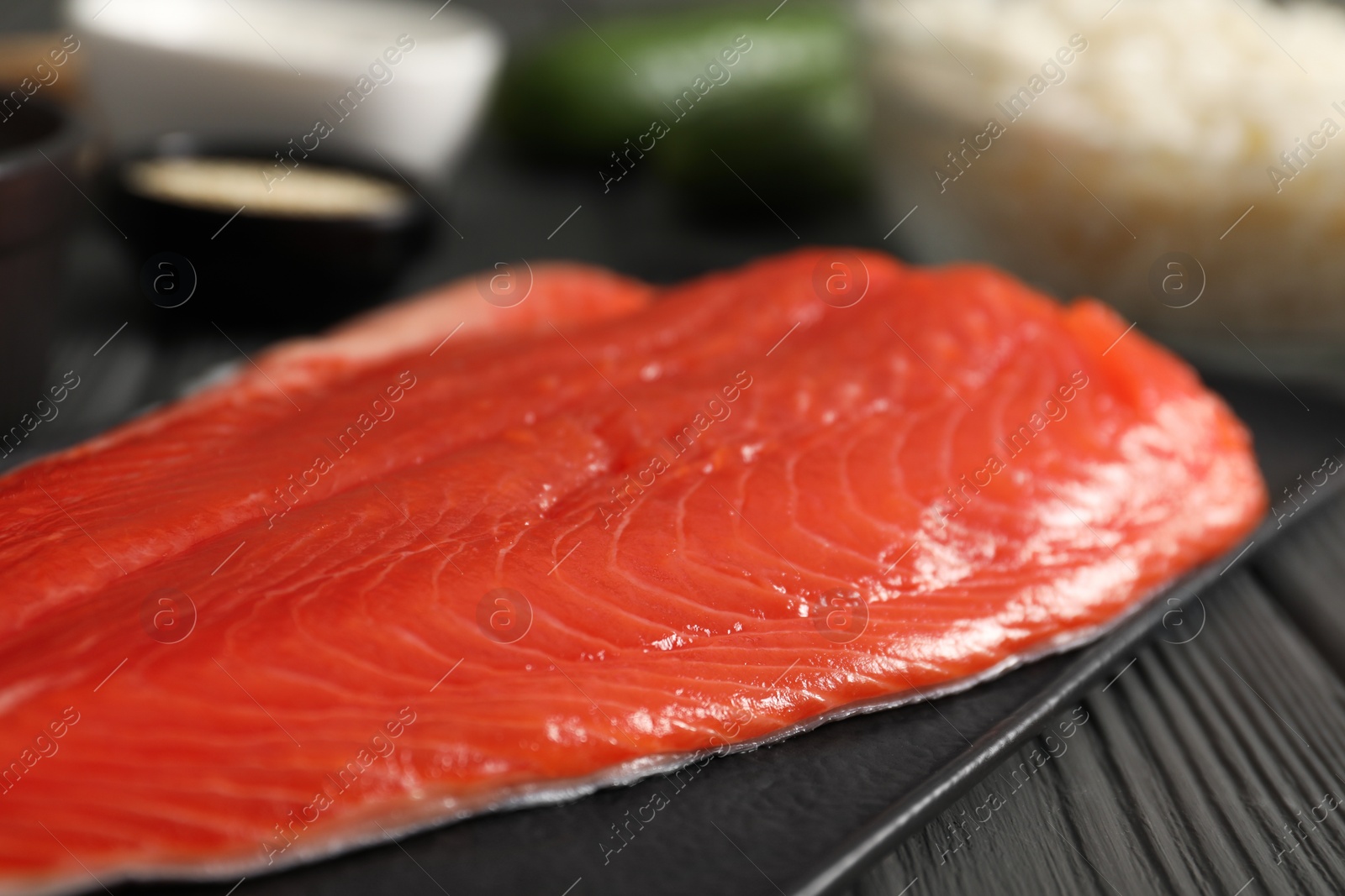 Photo of Fresh salmon for sushi on black wooden table, closeup