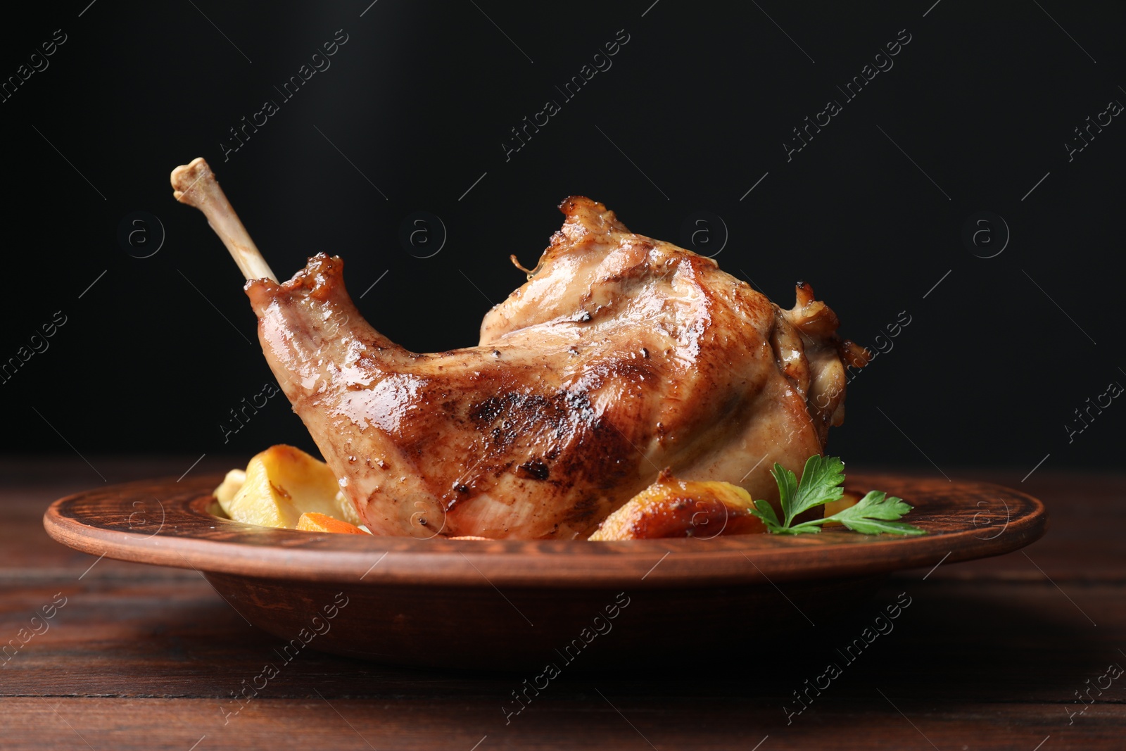 Photo of Tasty cooked rabbit meat with potatoes on wooden table, closeup