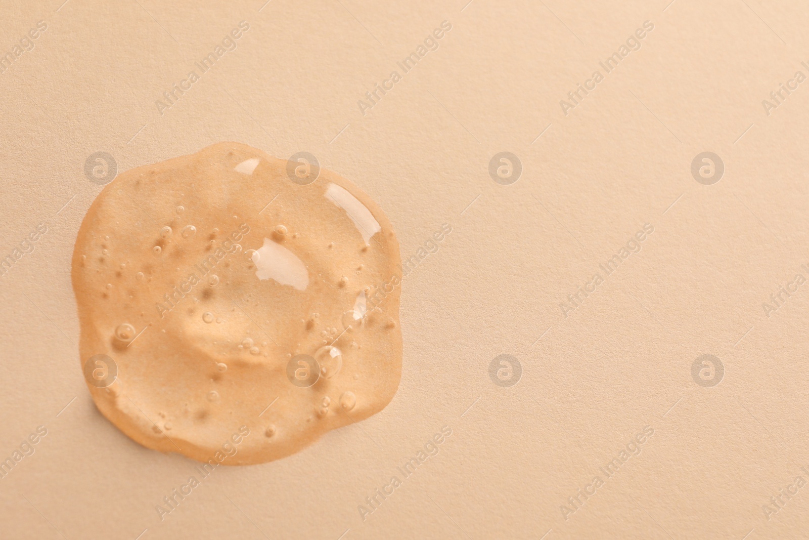 Photo of Sample of face gel on pale orange background, top view. Space for text