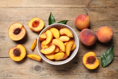Photo of Cut and whole juicy peaches on wooden table, flat lay