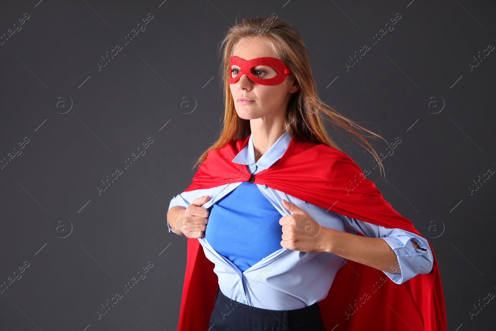 Photo of Confident businesswoman wearing superhero costume under suit on grey background