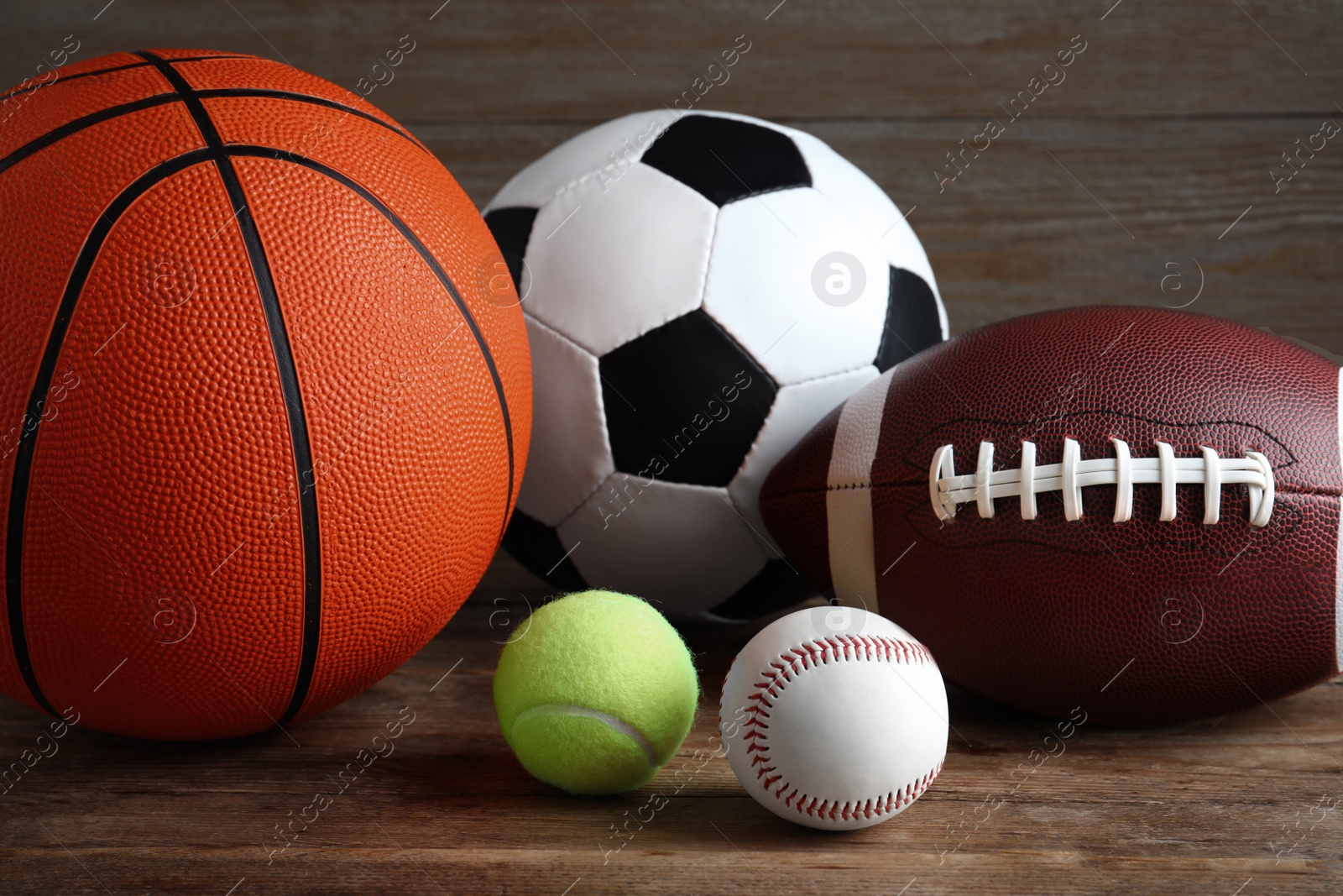 Photo of Set of different sport balls on wooden table, closeup