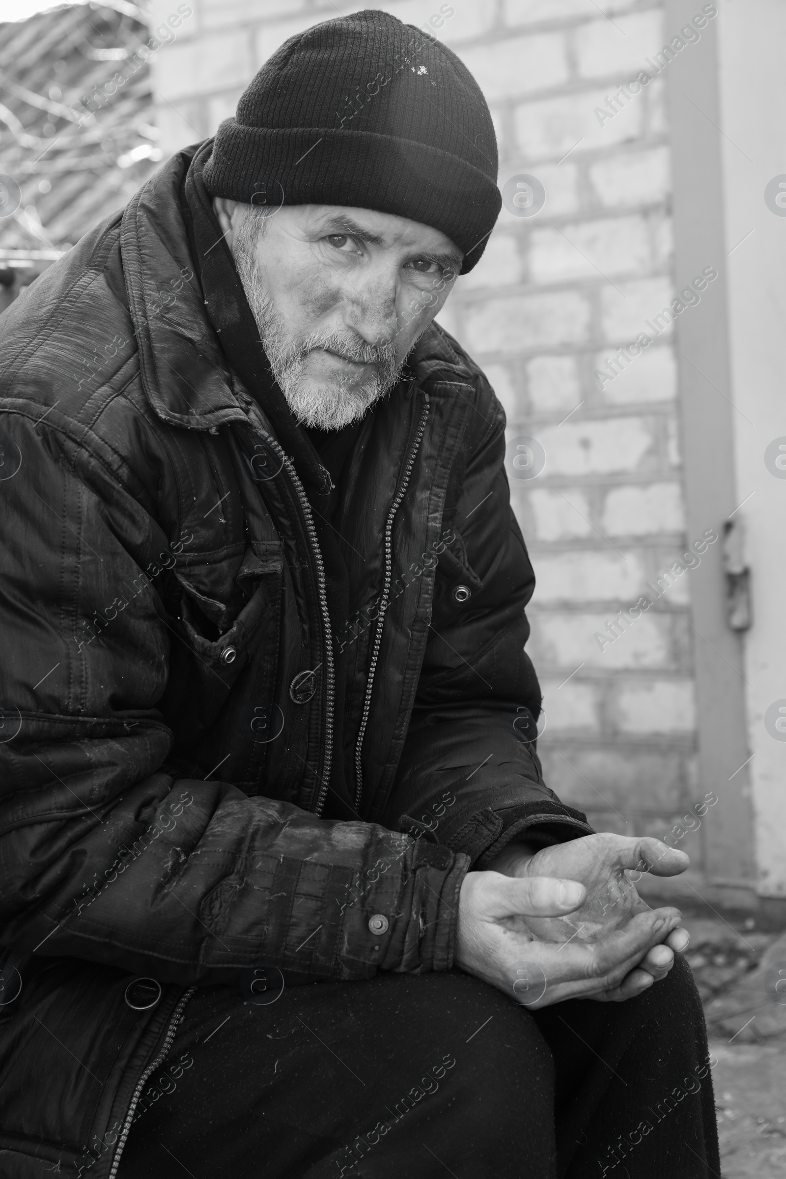 Photo of Poor homeless senior man holding coins outdoors. Black and white effect