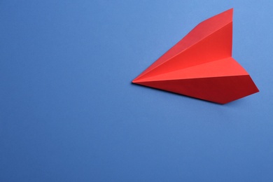 Photo of Red paper plane on blue background, top view. Space for text