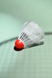 Photo of Plastic shuttlecock and shadow of racquet on light background, closeup. Badminton equipment