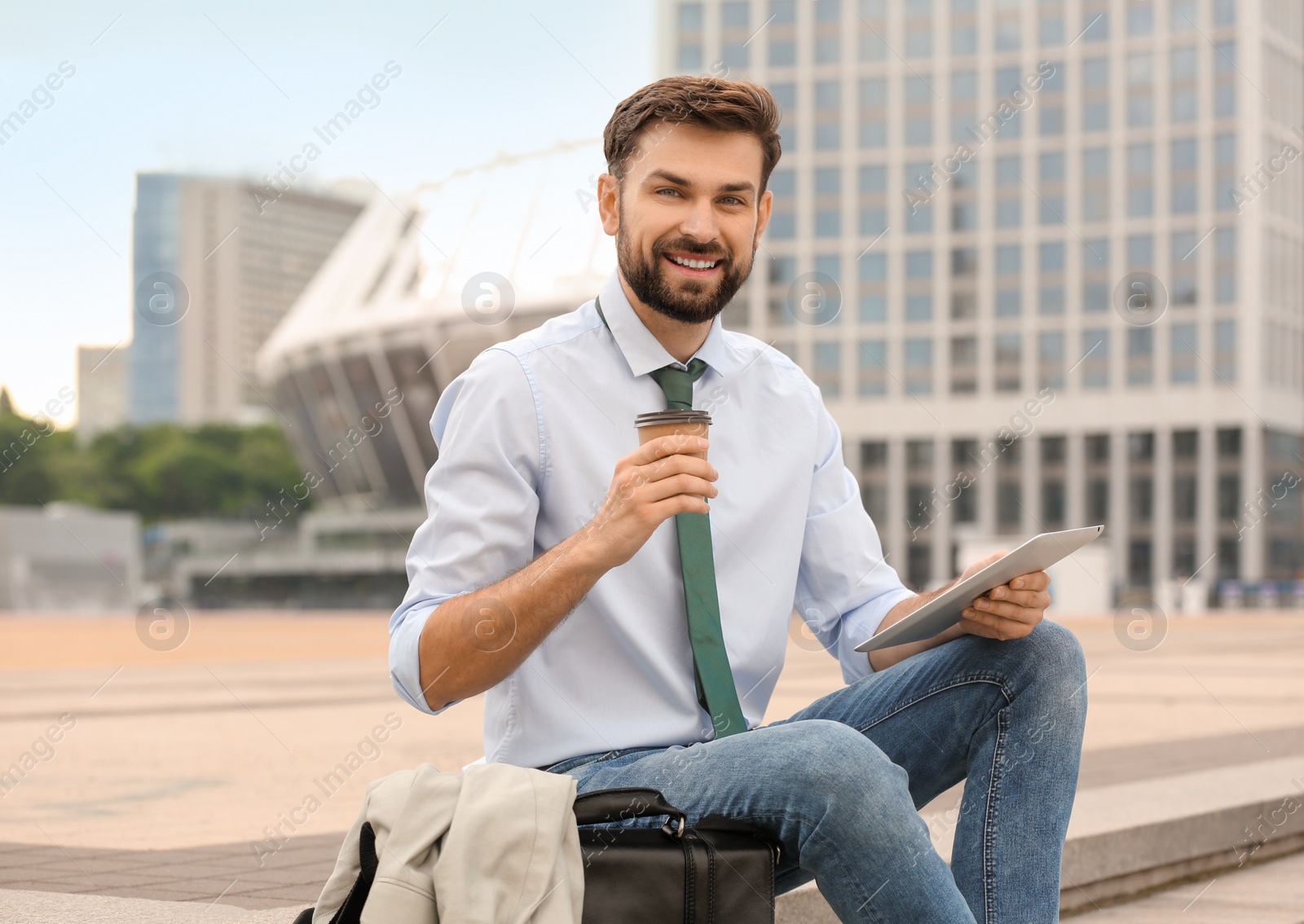 Photo of Handsome man working with tablet on city street