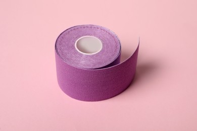 Photo of Bright kinesio tape in roll on pink background