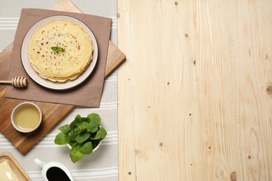 Photo of Delicious crepes with mint and honey on wooden table, flat lay. Space for text