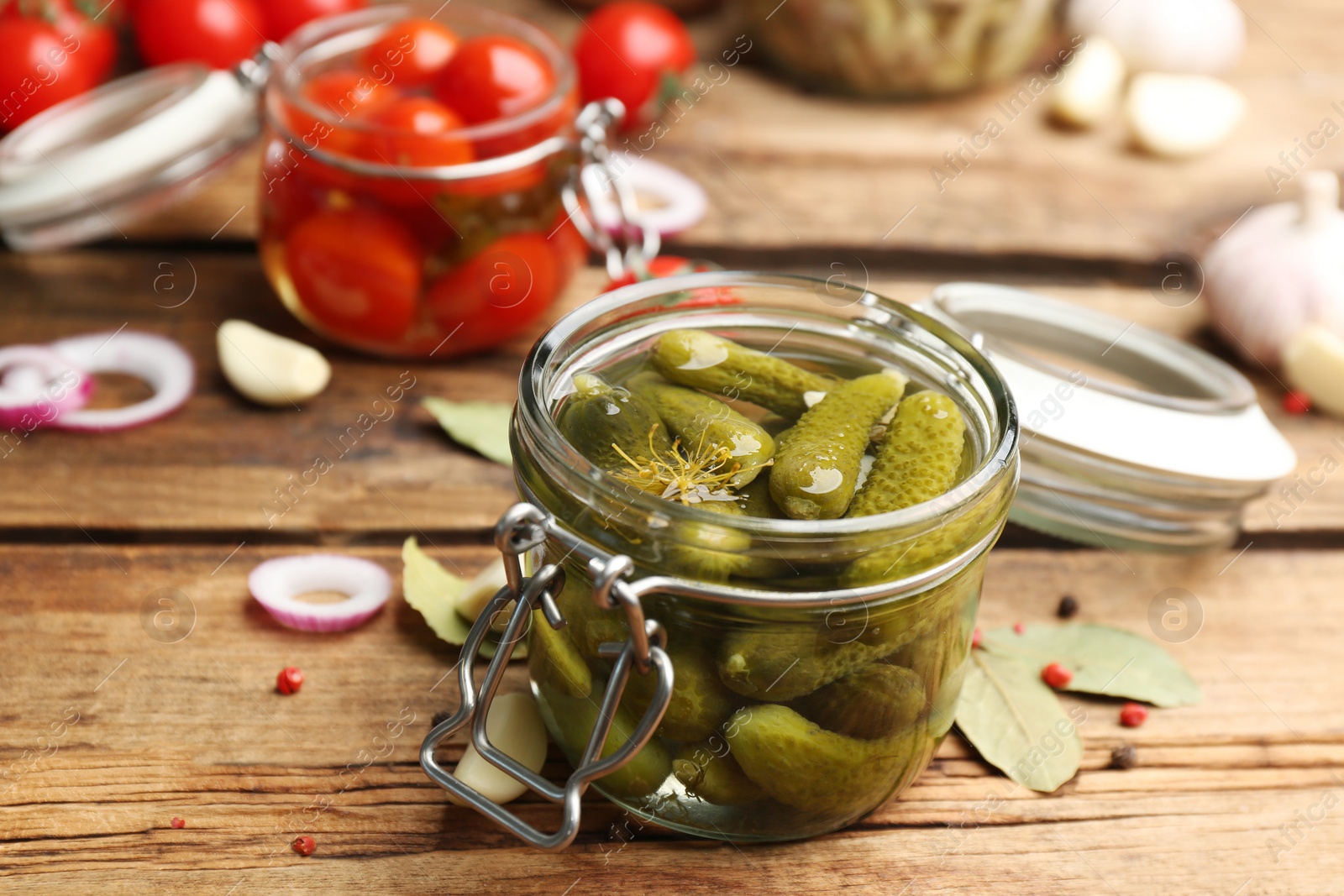 Photo of Glass jar of pickled cucumbers on wooden table