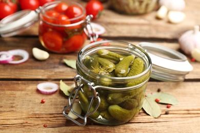 Glass jar of pickled cucumbers on wooden table