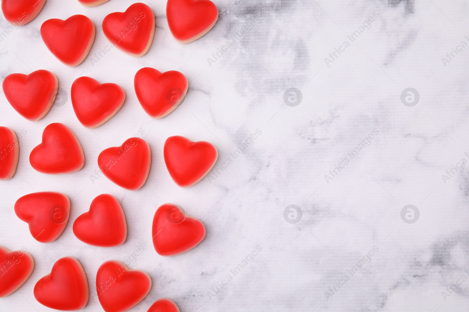 Photo of Delicious heart shaped jelly candies on white marble table, flat lay. Space for text