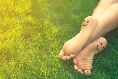Photo of Teenage girl with smiling faces drawn on heels outdoors, closeup. Space for text