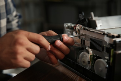 Repairman with screwdriver fixing modern printer, closeup