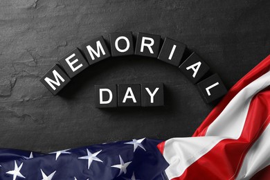 Photo of Cubes with phrase Memorial Day and American flag on black table, flat lay