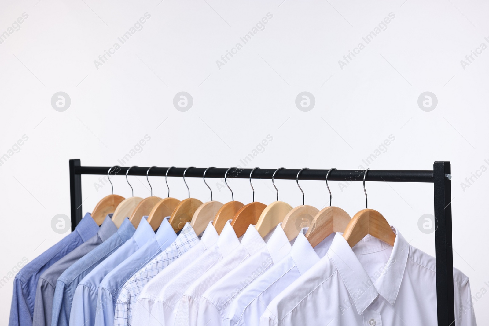 Photo of Dry-cleaning service. Many different clothes hanging on rack against white background, space for text