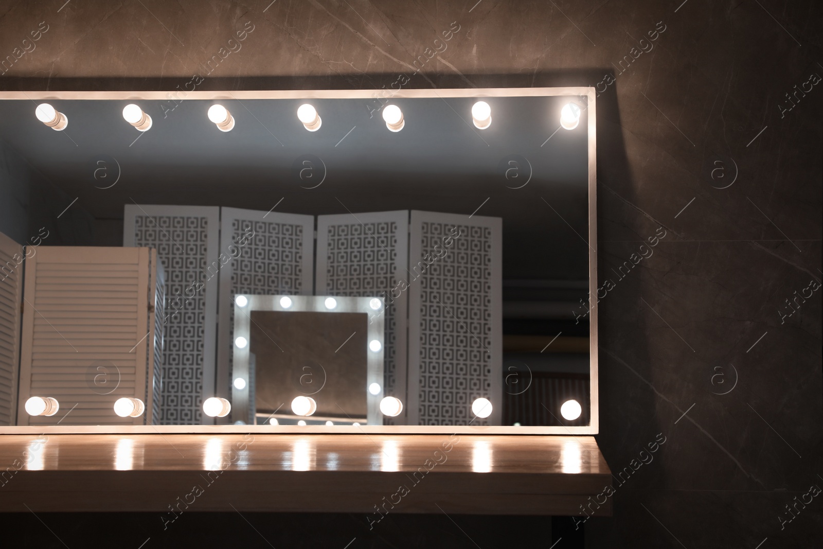 Photo of Modern mirror with light bulbs on wooden table in room