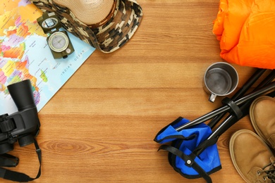 Flat lay composition with sleeping bag and camping equipment on wooden background. Space for text