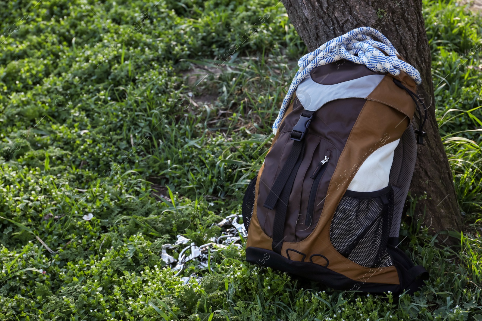 Photo of Backpack with climbing equipment on green grass outdoors. Space for text