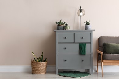 Photo of Room interior with grey chest of drawers near beige wall