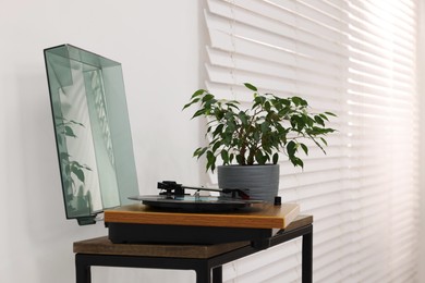 Photo of Record player and houseplant on wooden table at home