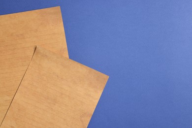 Photo of Sheets of old parchment paper on blue background, flat lay. Space for text