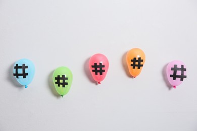 Photo of Bright balloons with hashtag symbols on white background