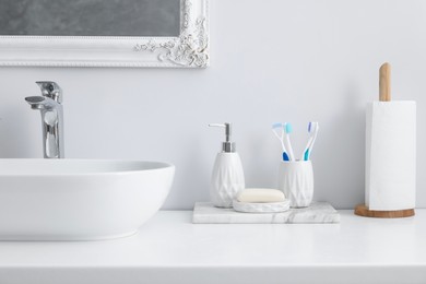 Different bath accessories and personal care products near sink on bathroom vanity