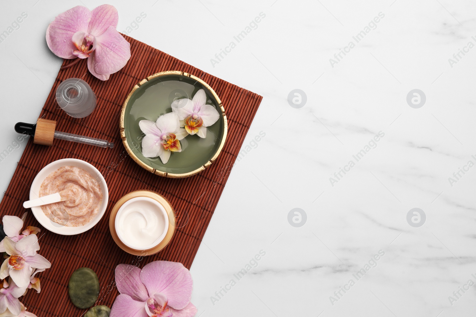 Photo of Composition with different spa products and flowers on white marble table, top view. Space for text