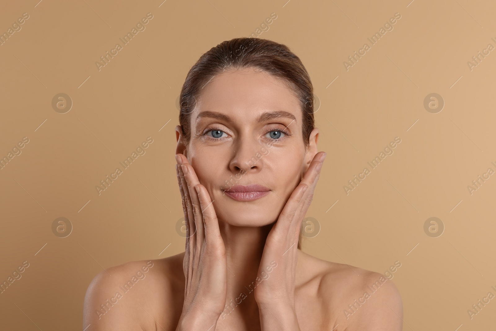 Photo of Woman massaging her face on beige background