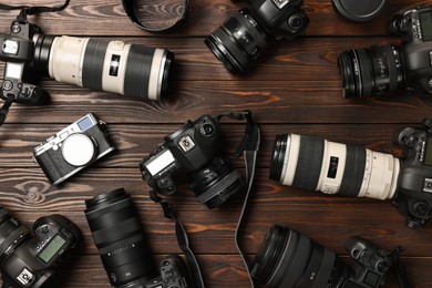 Modern cameras on wooden table, flat lay