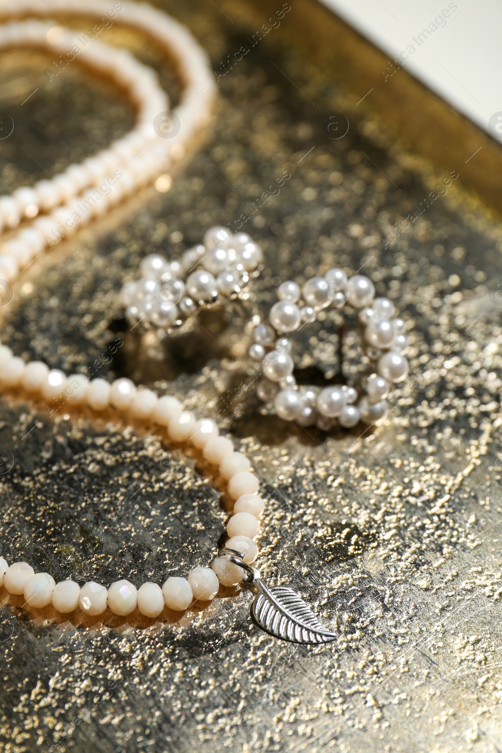 Photo of Beautiful necklace and earrings on golden surface, closeup