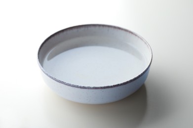 Beige bowl full of water on white background